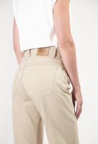 Beige MUD Jeans crafted from sustainable materials, showing a rear view of relaxed fit denim paired with a white sleeveless top.