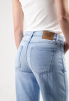 Light blue sustainable MUD Jeans made from organic cotton showing a close-up of back pockets and leather brand patch.
