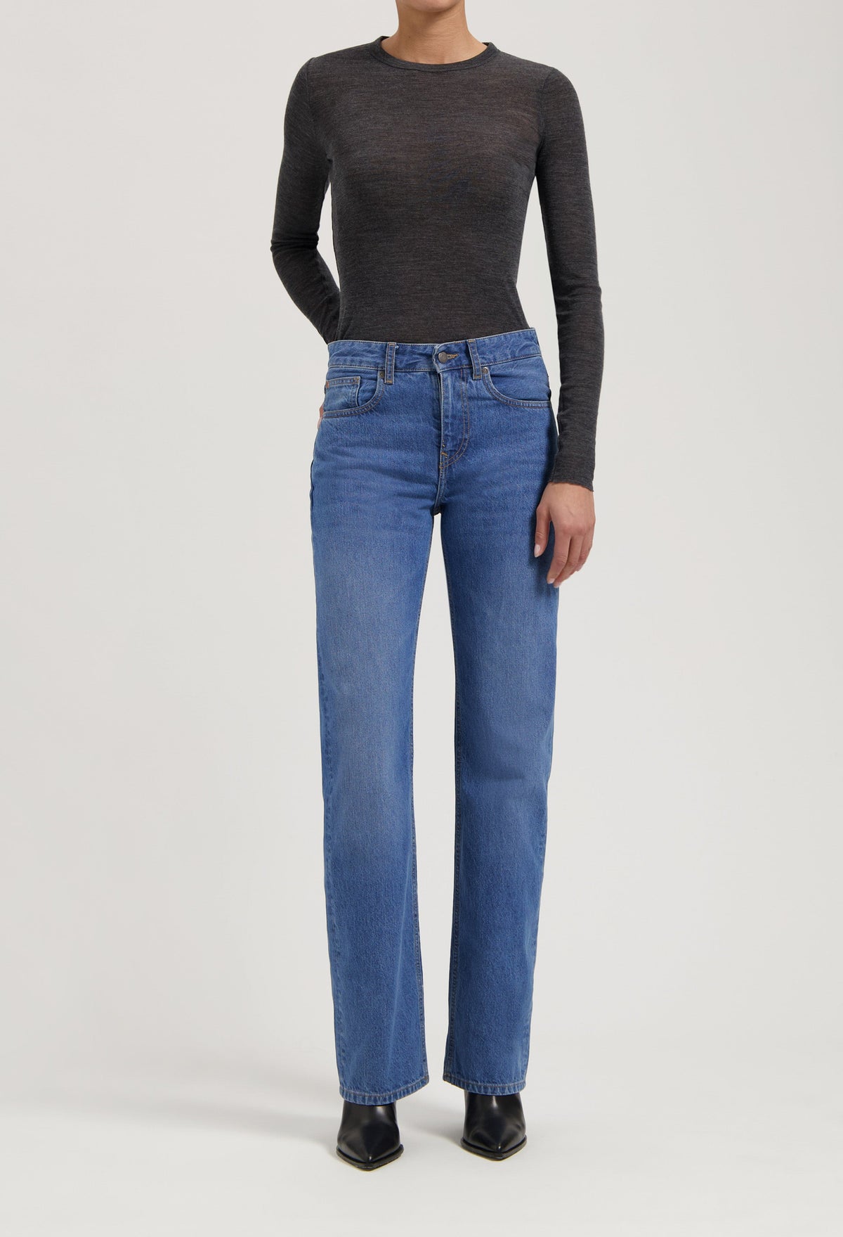 Dark gray fitted long-sleeve top paired with classic blue straight-leg jeans and black pointed-toe ankle boots.