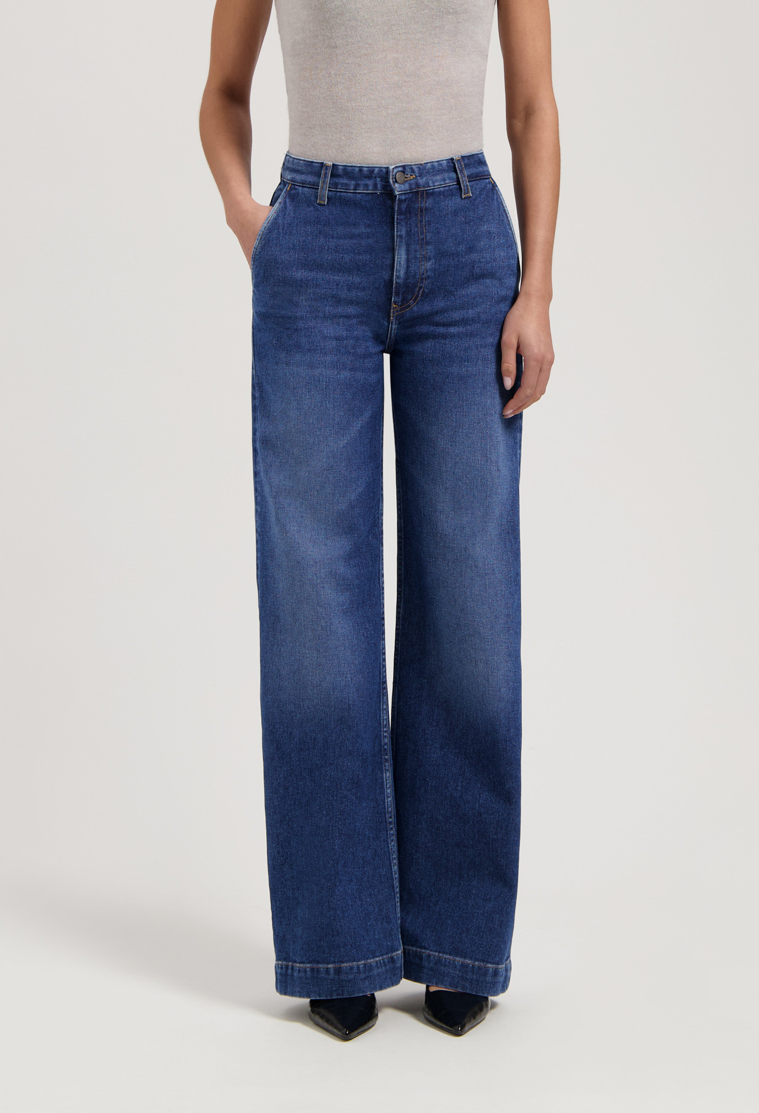 High-waisted blue wide-leg jeans made from denim, paired with a gray sleeveless top, showcasing casual chic fashion.