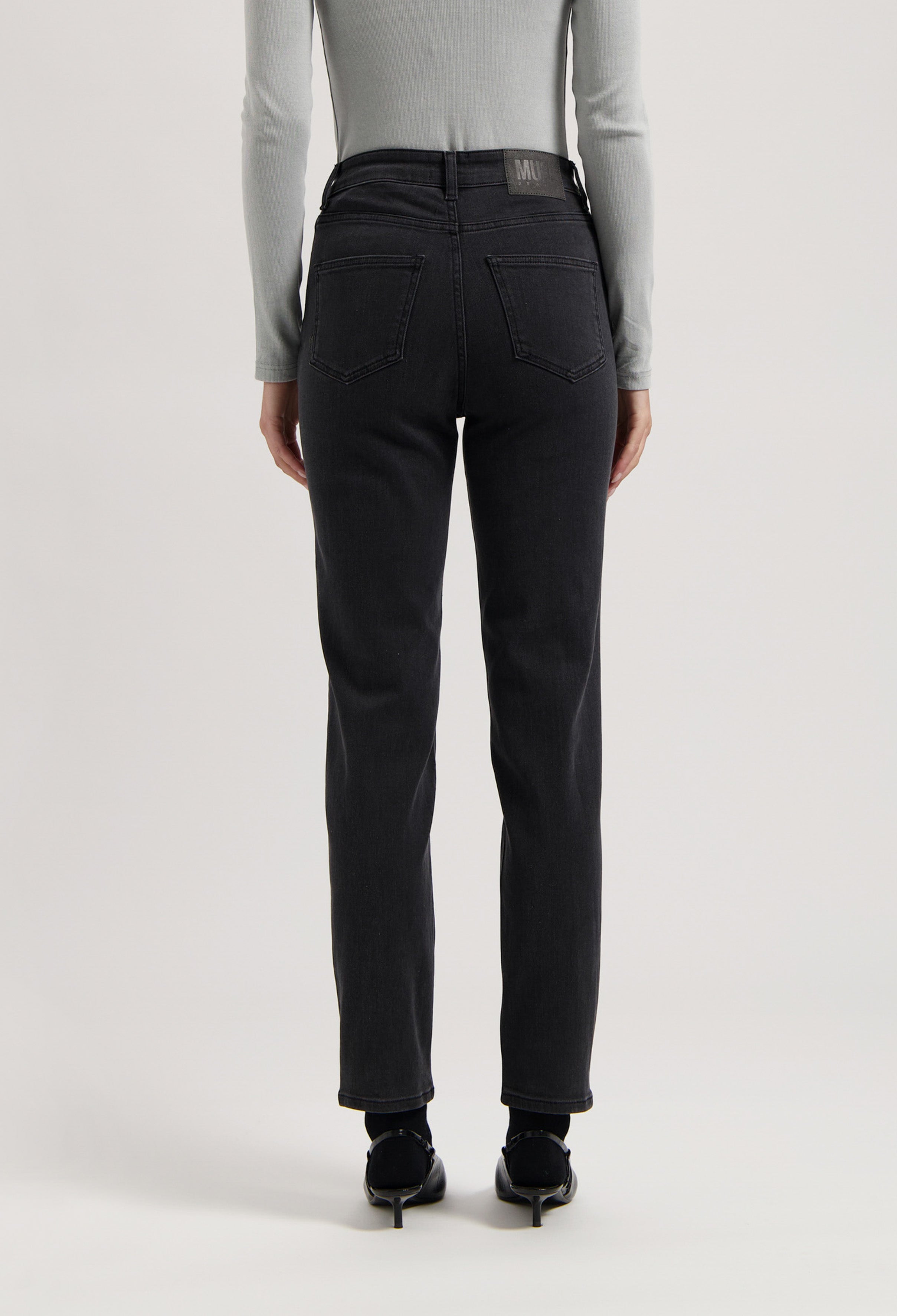 Back view of black, high-waisted denim jeans worn with a fitted gray long-sleeve top, showcasing modern casual fashion.