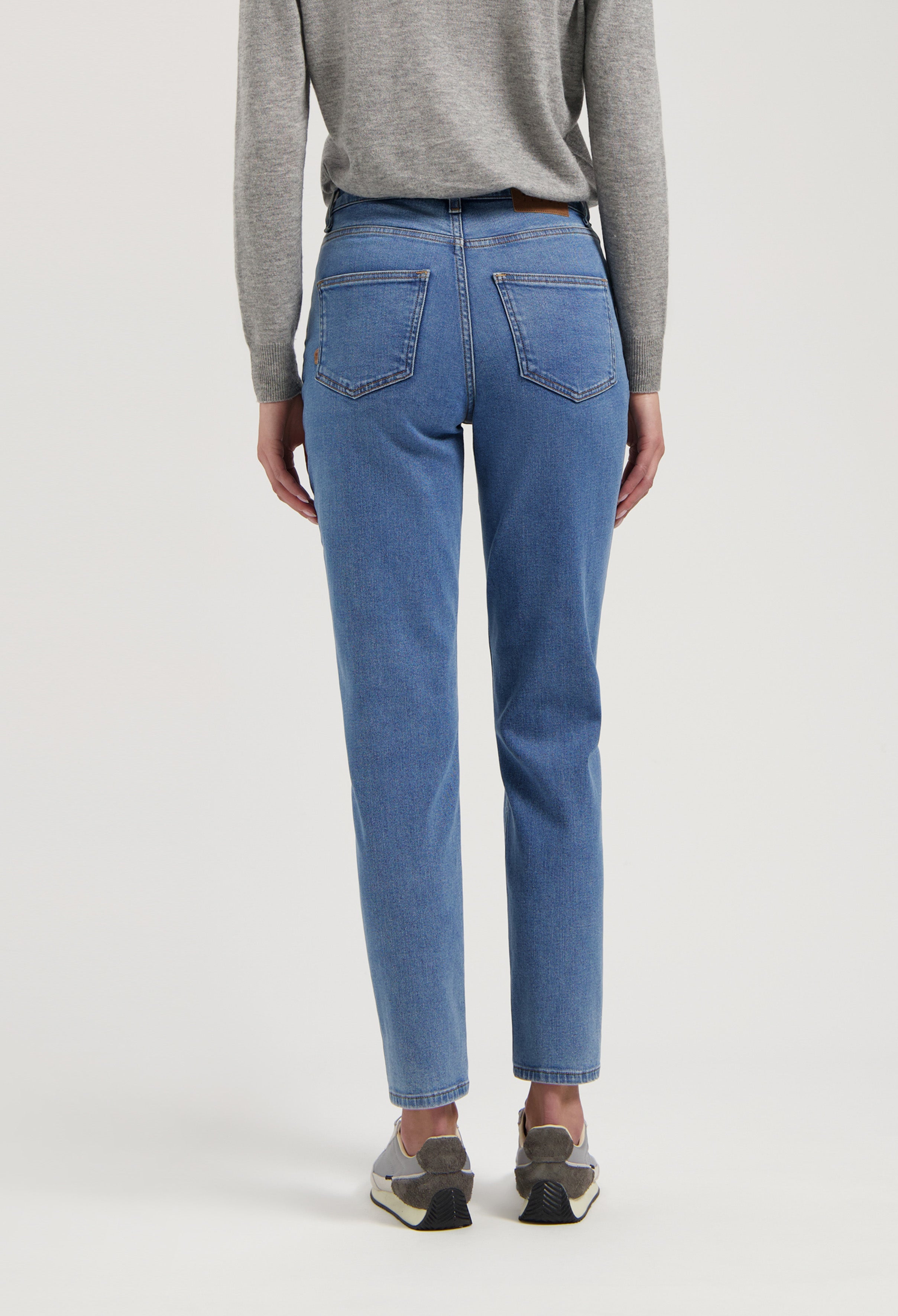 Casual light blue straight-leg jeans paired with a cozy gray sweater, showcasing a modern, comfortable everyday style.