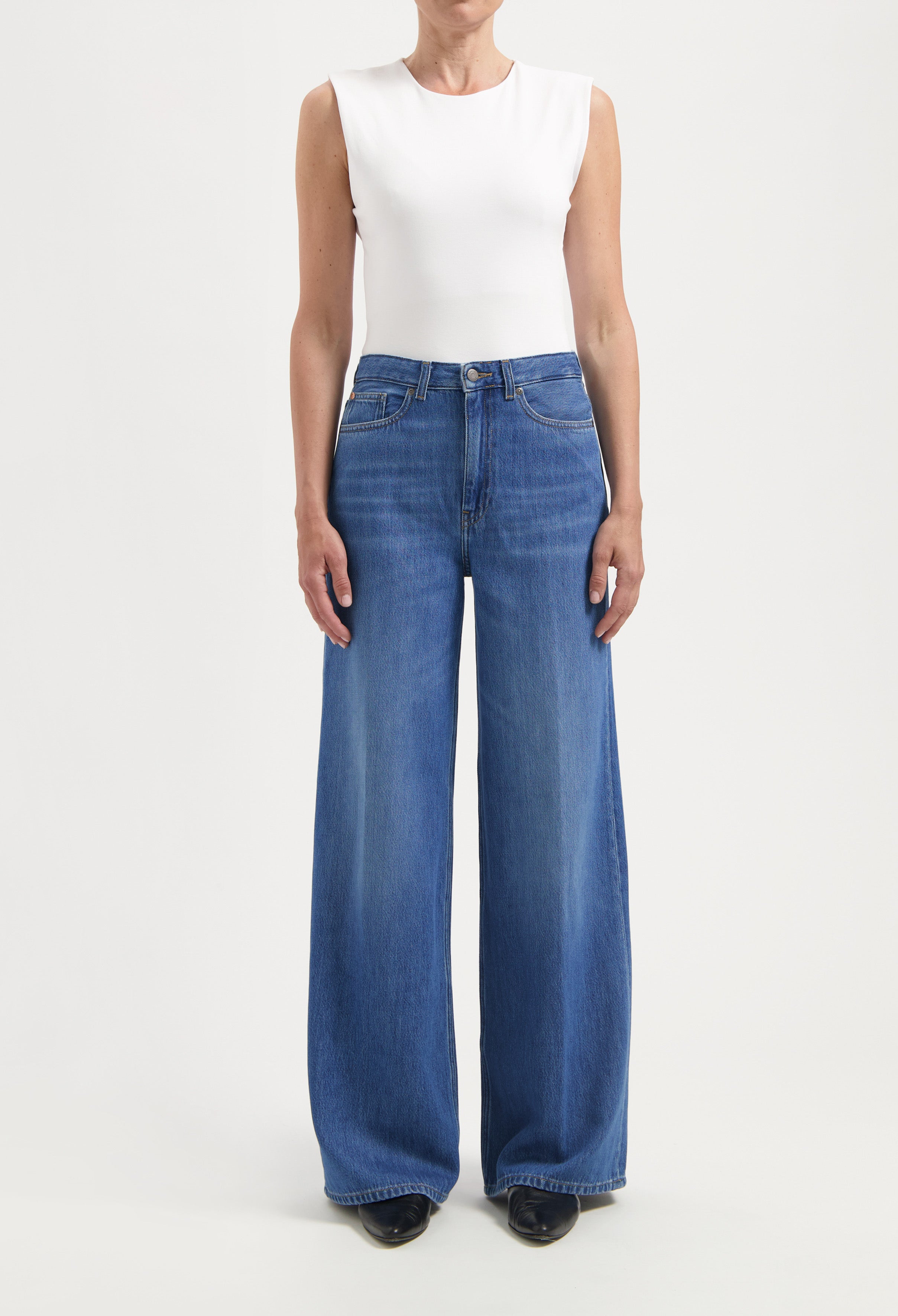 Wide-leg blue denim jeans paired with a white sleeveless top, showcasing a casual yet stylish outfit.