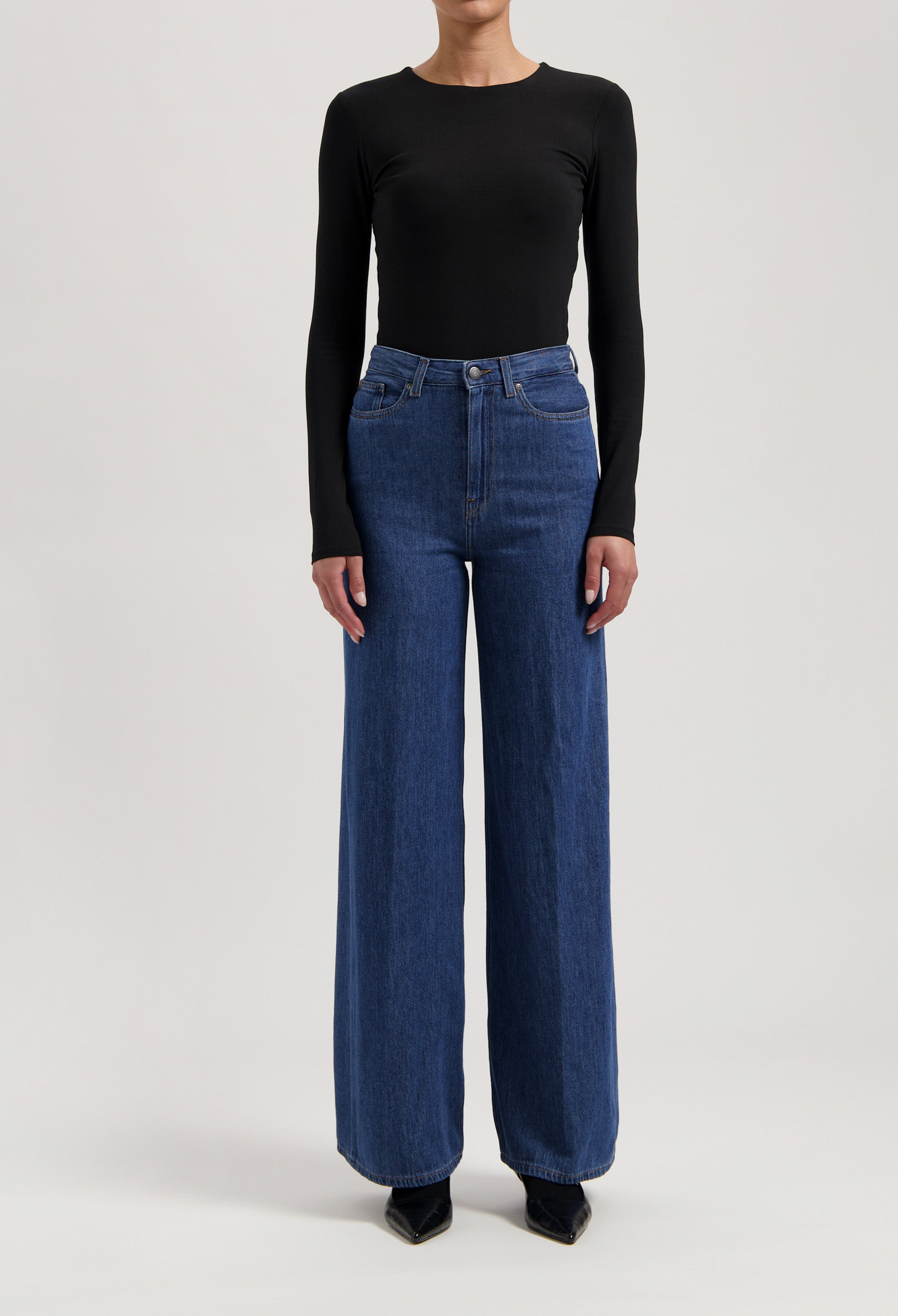 A stylish outfit featuring high-waisted, wide-leg blue jeans paired with a fitted, long-sleeve black top.