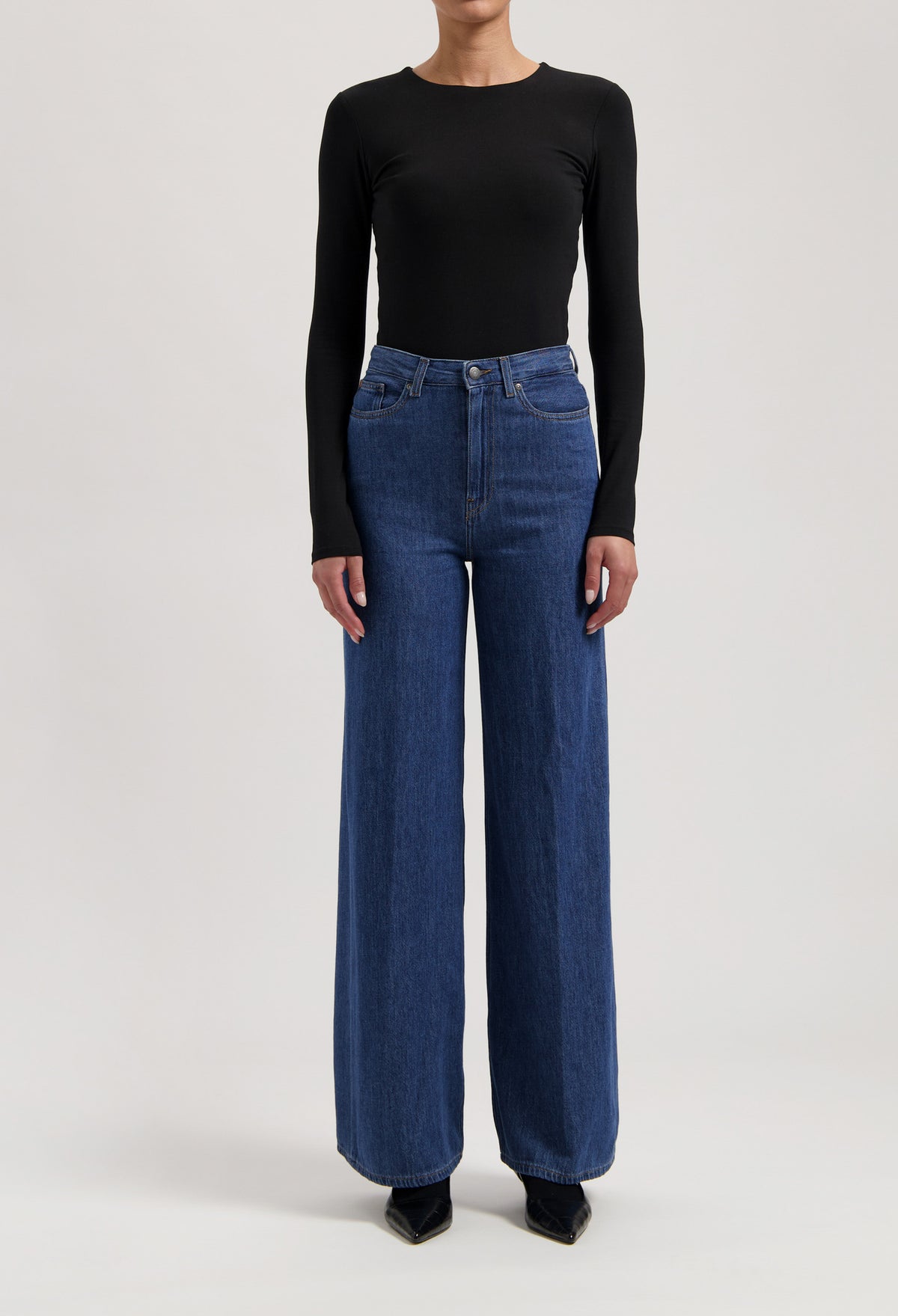 A stylish outfit featuring high-waisted, wide-leg blue jeans paired with a fitted, long-sleeve black top.