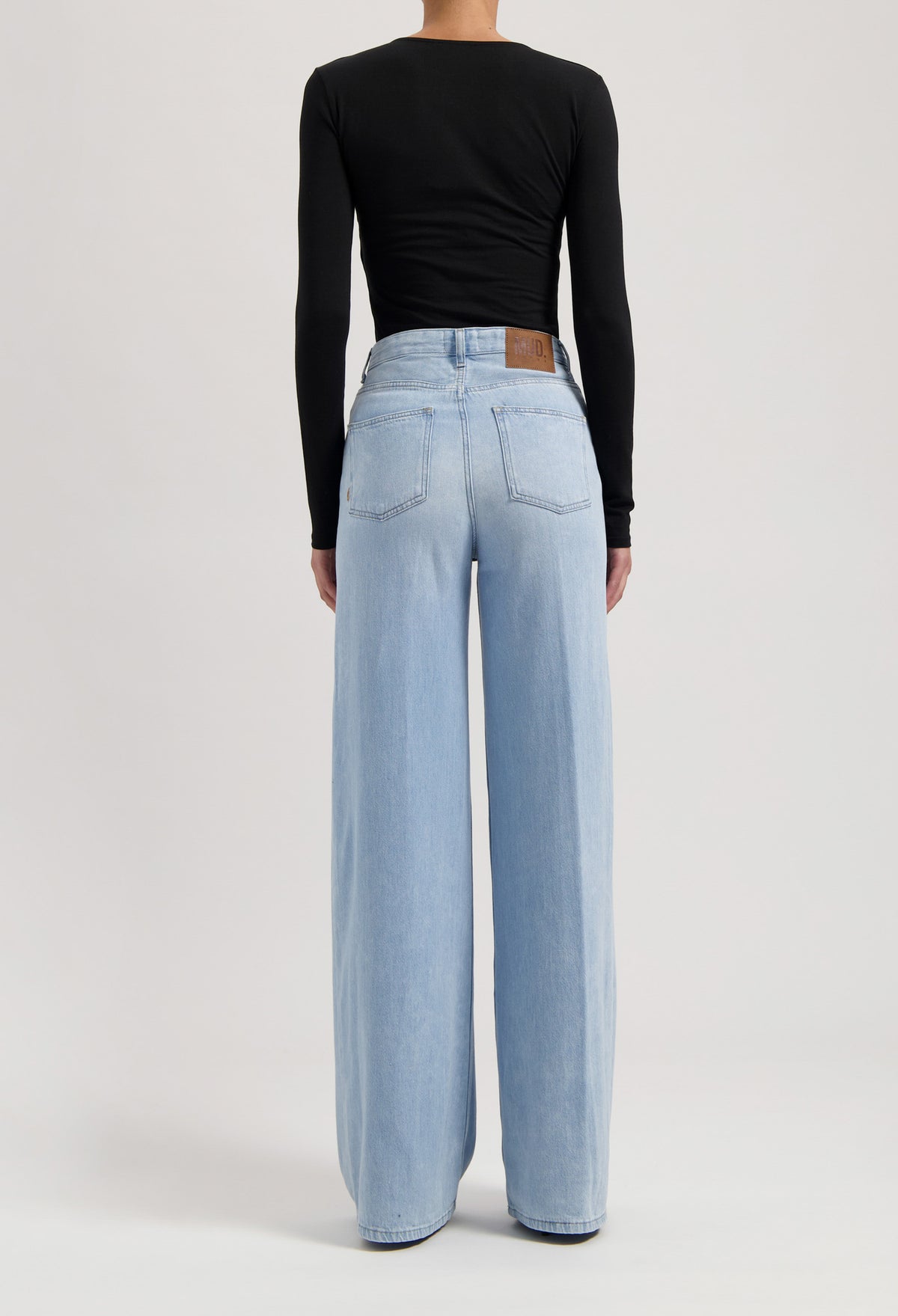 High-waisted wide-leg jeans in light blue denim paired with a sleek black long-sleeve top, showcasing sustainable fashion.