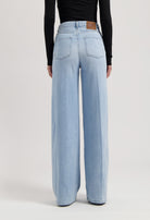 Wide-leg light blue denim jeans with a high waist and sustainable materials, paired with a fitted black top.