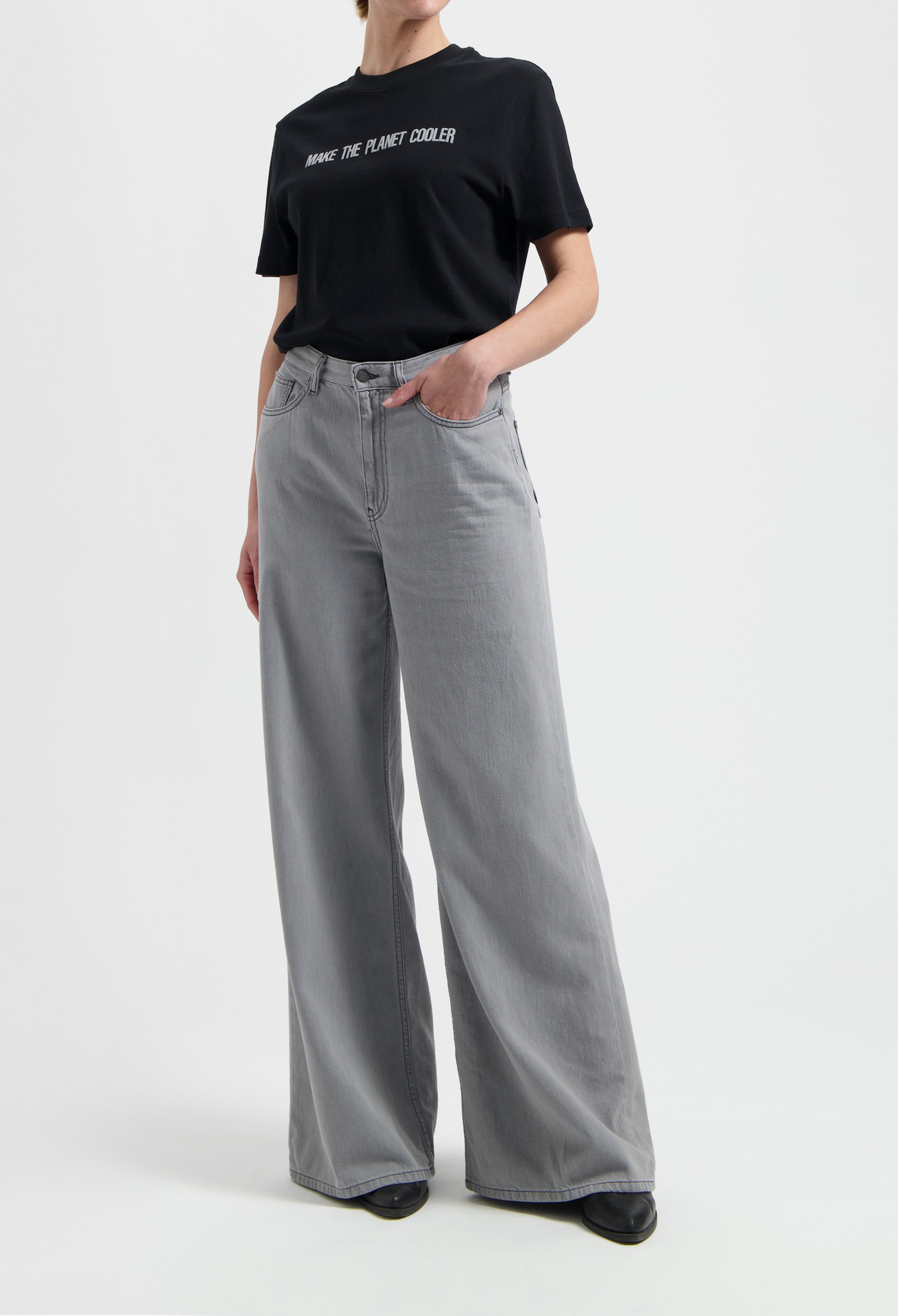 Model wearing a black slogan t-shirt and light gray wide-leg jeans, showcasing casual chic fashion style.