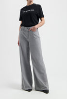 Model wearing a black slogan t-shirt and light gray wide-leg jeans, showcasing casual chic fashion style.