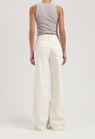 Back view of flared white denim pants worn with a light gray sleeveless top, showcasing modern and stylish casualwear.