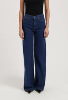 Wide-leg blue denim jeans paired with a black sleeveless top, showing high-waisted style and casual elegance.