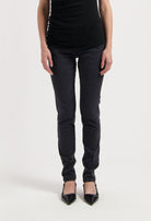 Chic black slim-fit pants paired with a sleeveless top and pointed black heels on white background, highlighting stylish casual wear.