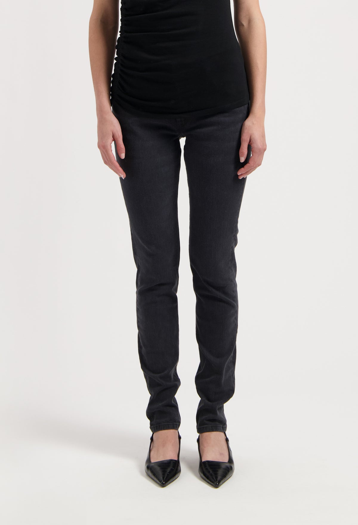 Chic black slim-fit pants paired with a sleeveless top and pointed black heels on white background, highlighting stylish casual wear.