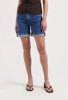 Casual blue denim shorts paired with a brown t-shirt and black sandals, showcasing a relaxed summer look.