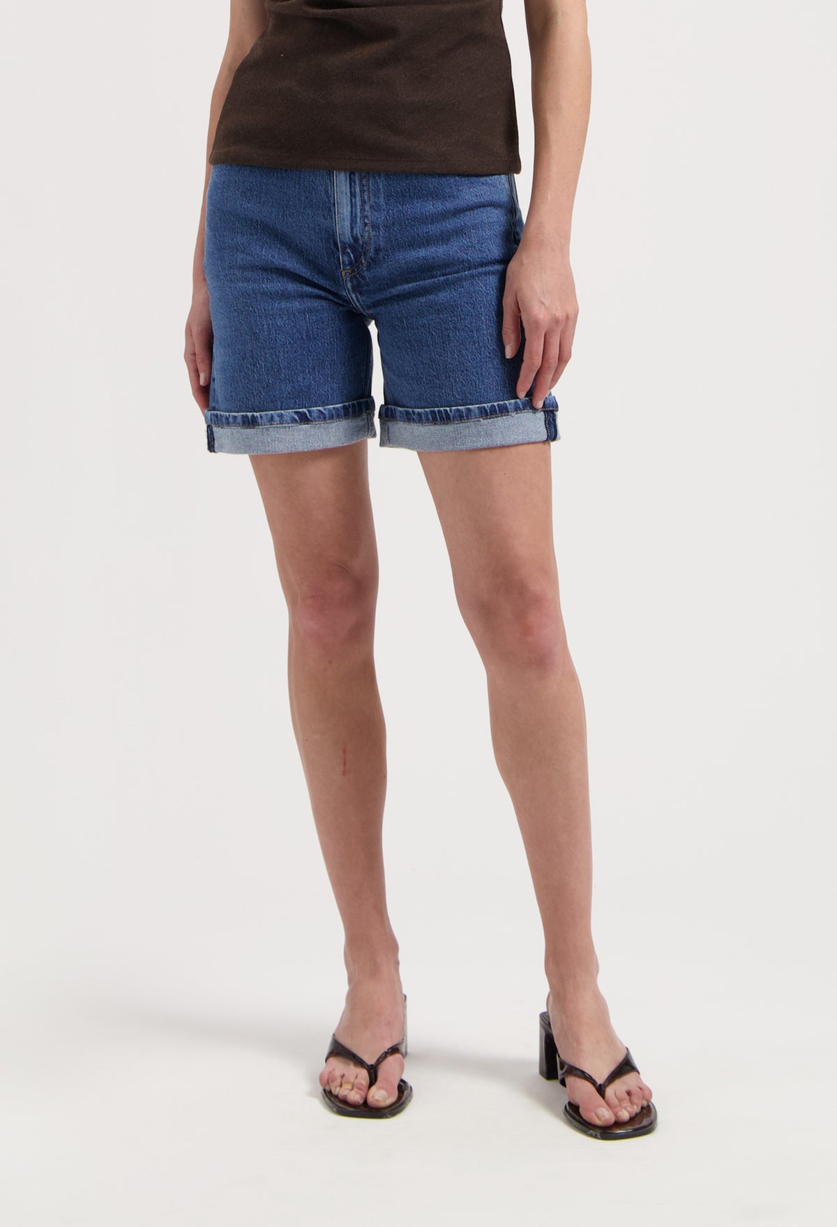 Casual blue denim shorts paired with a brown t-shirt and black sandals, showcasing a relaxed summer look.