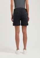 Dark denim shorts with rolled cuffs worn with a fitted gray top, highlighting casual summer fashion in white sneakers.
