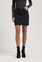 Woman wearing a black denim skirt paired with a fitted gray long-sleeve top and black ankle boots.