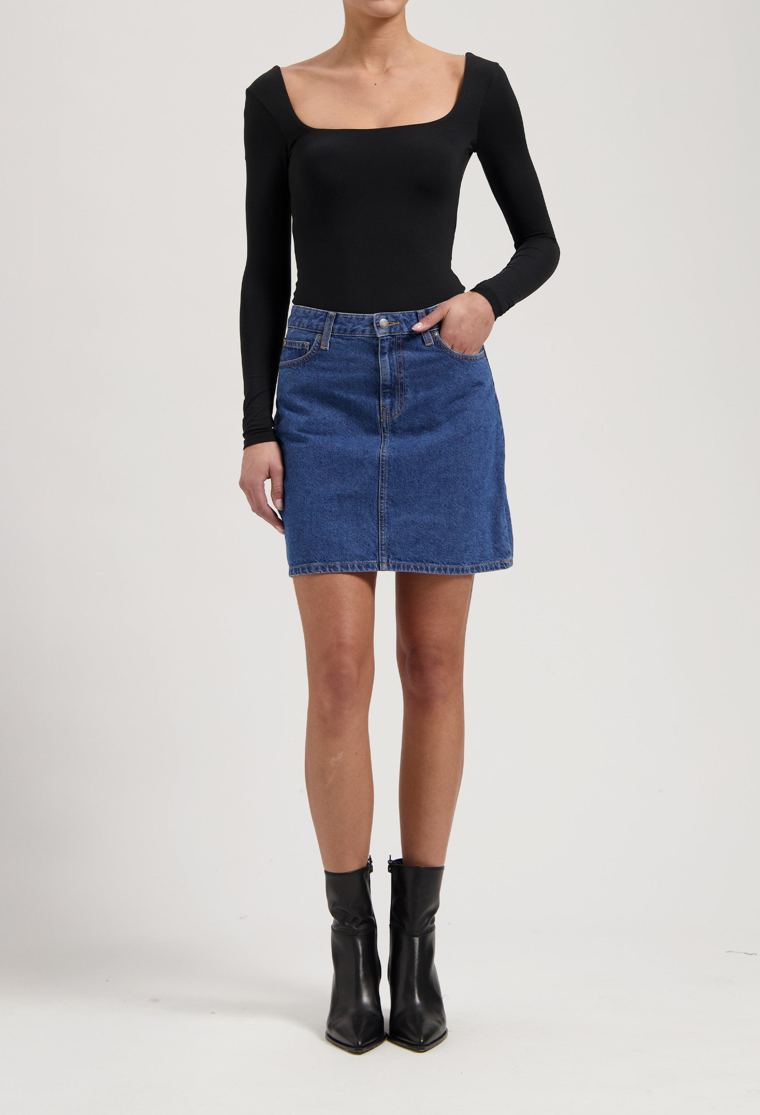 A-line denim skirt with classic blue wash paired with a fitted black long-sleeve top and sleek black ankle boots.