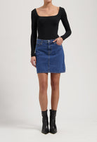 A-line denim skirt with classic blue wash paired with a fitted black long-sleeve top and sleek black ankle boots.