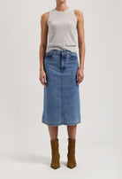 Mid-length denim skirt in blue paired with a sleeveless gray top, styled with brown suede ankle boots on a white background.
