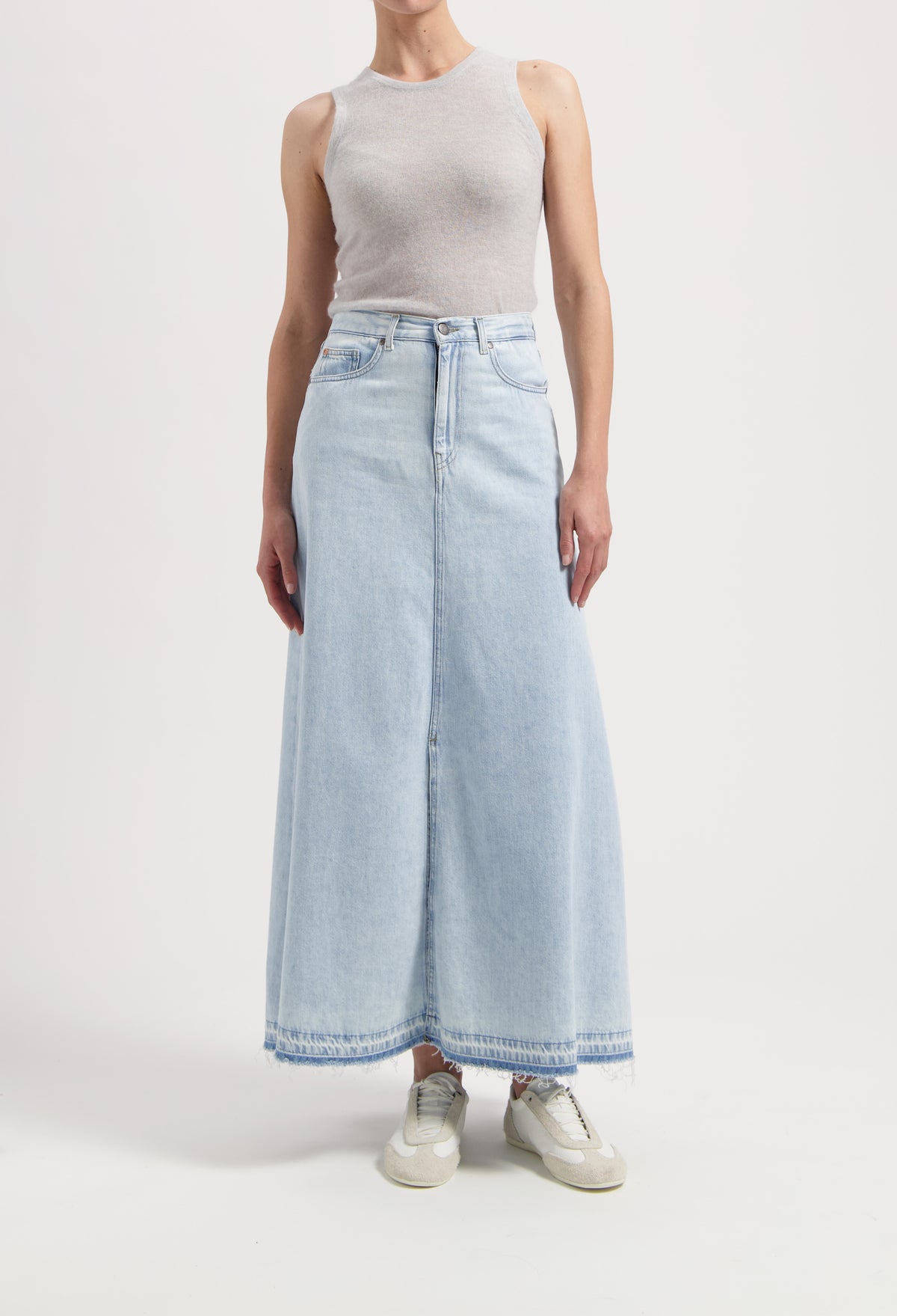 Light blue denim maxi skirt paired with a sleeveless gray top, styled with casual beige sneakers.