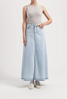 Light blue, high-waisted denim maxi skirt paired with a sleeveless gray top, showcasing casual and stylish wear.