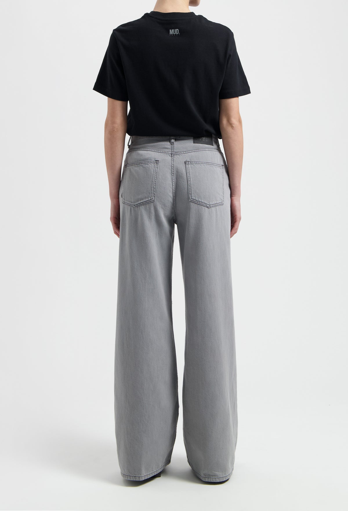 Sustainable MUD Jeans in beige, crafted from organic cotton, offering a tailored fit, paired with a gray T-shirt.